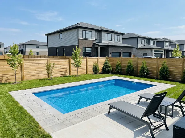 Newer fibreglass inground pool in a tidy Caledonia suburban backyard with young trees