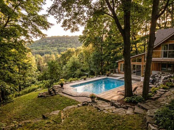 Residential pool in a hilly Dundas backyard with mature trees and the Niagara Escarpment in the background