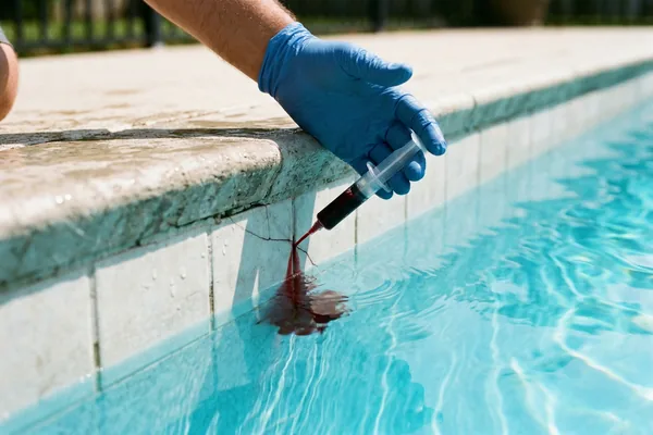 Pool technician performing a dye test at the waterline to confirm a leak location